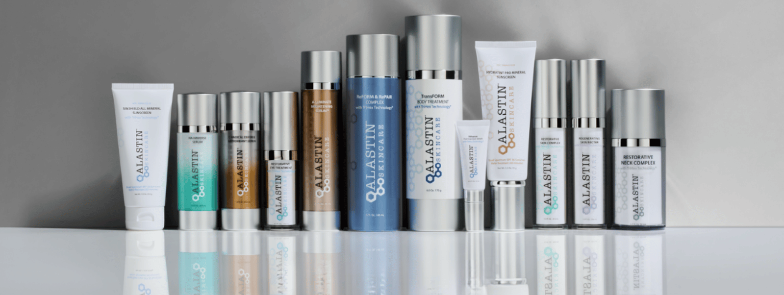 Row of skincare products on a reflective surface with a neutral background