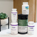 A stack of five dietary supplement bottles and jars from Biote Nutritionals and Thorne, arranged on a white surface with a small potted succulent in the background.