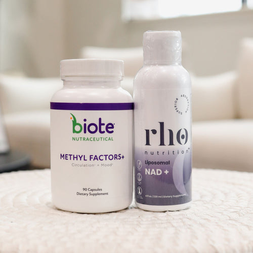 Two white supplement bottles standing side by side on a textured white surface in a softly blurred indoor setting. The left bottle is labeled biote Nutraceutical Methyl Factors+ and the right bottle is labeled rho nutrition Liposomal NAD+.