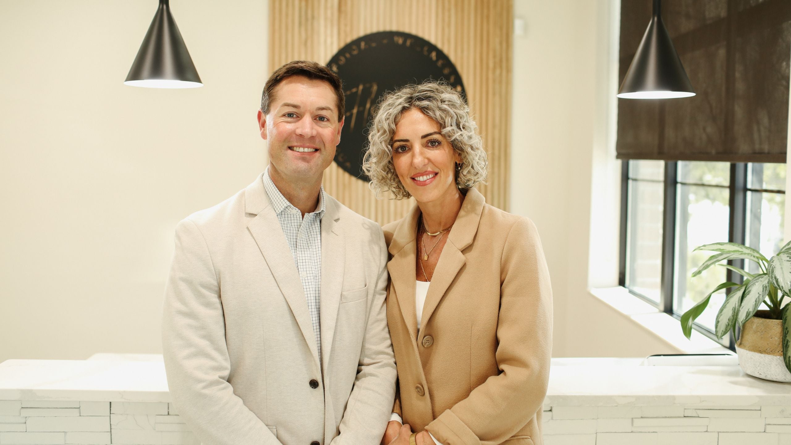 Two people standing in a modern office setting with neutral decor.