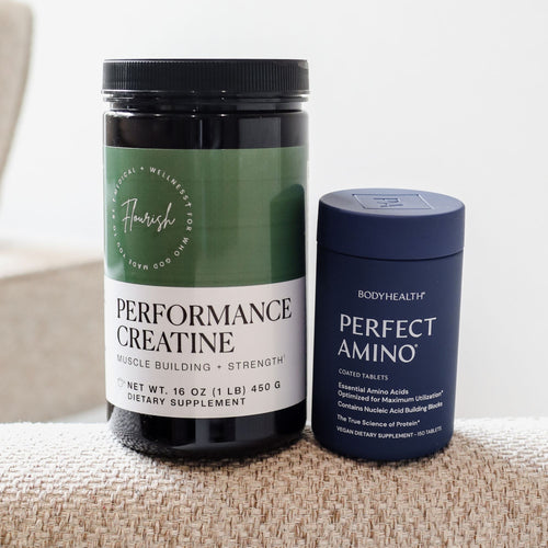 Two dietary supplement containers on a woven beige surface: a larger black tub labeled Freshly Made Performance Creatine with a green-and-white label, and a smaller dark blue tub labeled BodyHealth Perfect Amino with a blue lid.