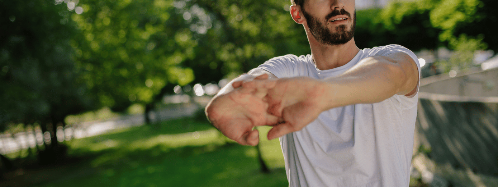 Man stretching outdoors in a park with greenery