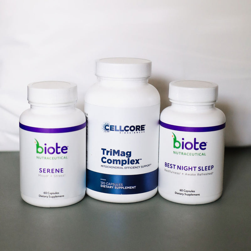 Three white dietary supplement bottles on a gray surface against a white background: a biote Serene bottle on the left, a Cellcore TriMag Complex bottle in the center, and a biote Best Night Sleep bottle on the right.