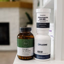 Three dietary supplement bottles standing on a white surface in a softly blurred indoor setting: an amber bottle labeled Thyro Activate, a white bottle labeled Pendulum Akkermansia 500 EC, and a white bottle labeled Cellcore GCO.